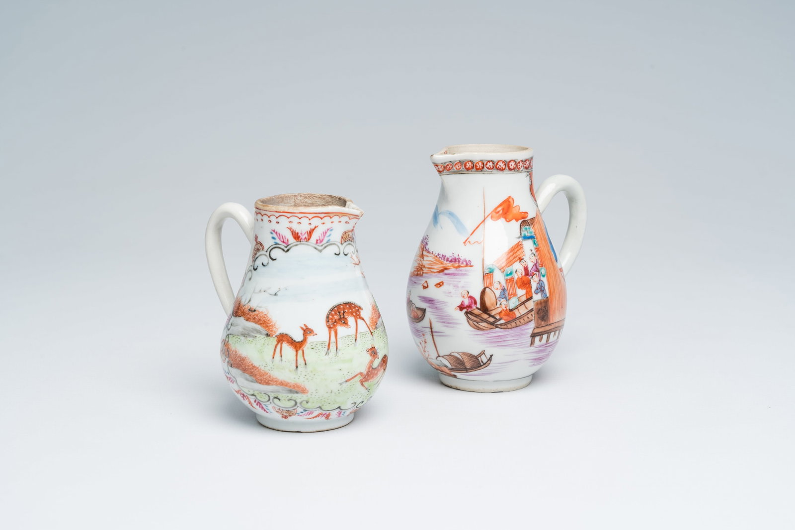 Two Chinese famille rose milk jugs with 'Mandarin' design and deer in a landscape, Qianlong: Full title: Two Chinese famille rose milk jugs with 'Mandarin' design and deer in a landscape, Qianlong Description: H 10,7 - 9,2 cm Provenenance: -The 'Mandarin' milk jug with a 'Denys Cowell, 60 Mid