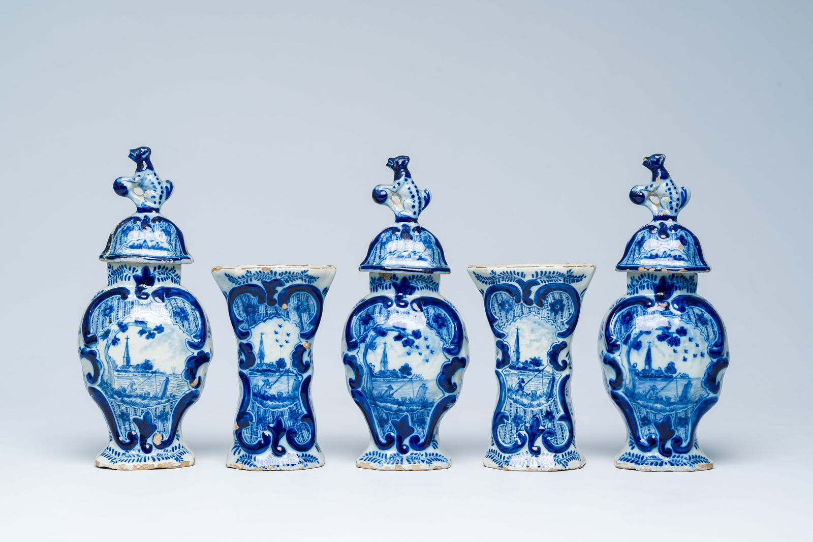 A Dutch Delft blue and white five-piece vase garniture with a fisherman in a landscape, 18th C.: H 24,5 - 15 cm (the tallest and the smallest vase) Condition reports and high resolution pictures are available on our website at www.coronariauctions.com. Further questions are always welcome at info