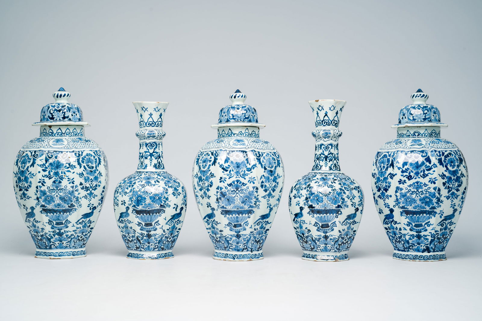 A Dutch Delft blue and white five-piece vase garniture with flower baskets and birds among: H 40 - 36 cm (the tallest and the smallest vase) Marked with an apocryphal 'AK' for Adrianus Kockx, owner of the Grieksche A factory from 1687 to 1701. Condition reports and high resolution pictures a