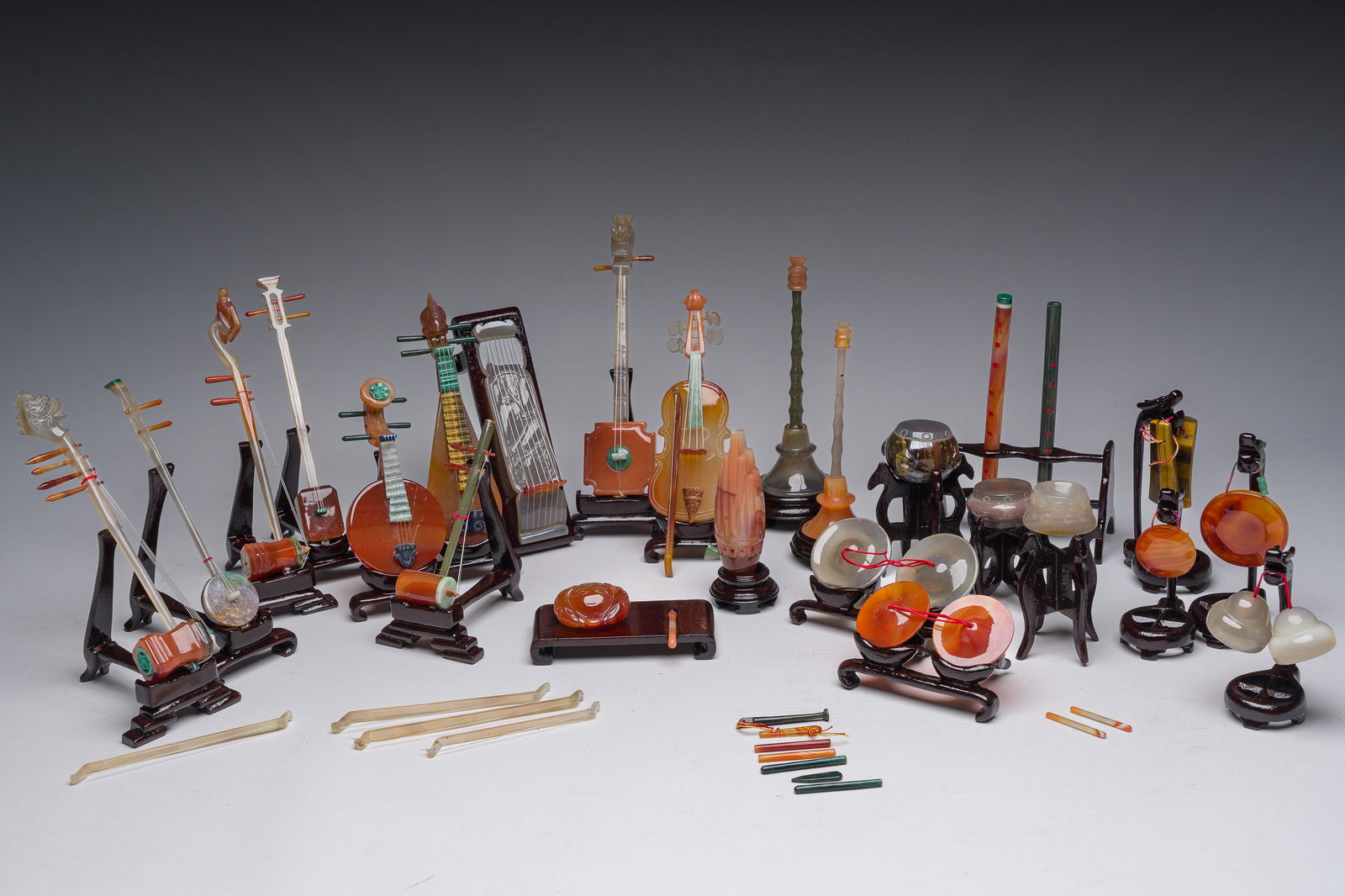 A Chinese collection of agate carved musical instruments with an accompanying presentation box,: A Chinese collection of agate carved musical instruments with an accompanying presentation box, Republic, 20th C. H 11,5 - L 49,5 - D 29,5 cm (the box)L 15,5 cm (the two stringed guitar excl. stand)L