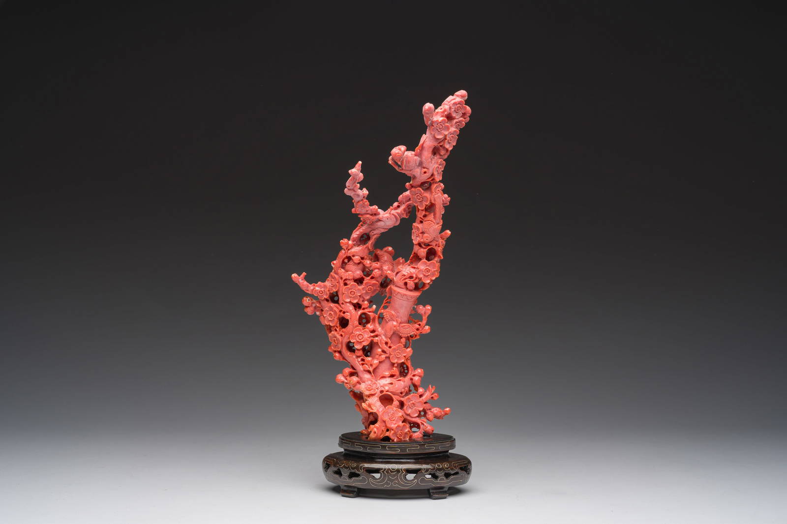 A Chinese red coral group of birds among blossoming branches on a silver-inlaid wooden stand,
