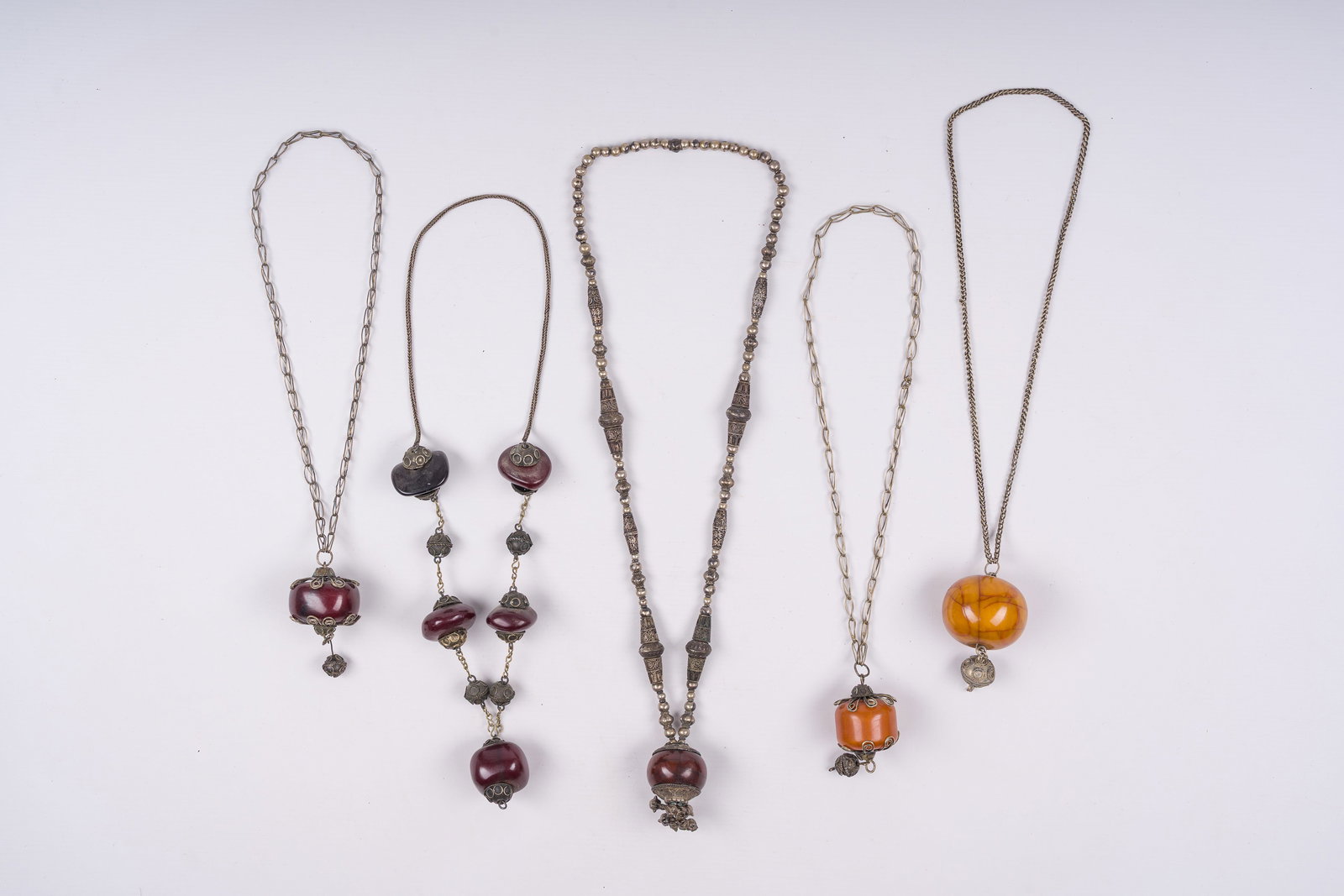 Five silver and copper necklaces with amber pendants, Morocco and Nepal, 19th/20th C.: Five silver and copper necklaces with amber pendants, Morocco and Nepal, 19th/20th C. L: 50 cm (the central example)