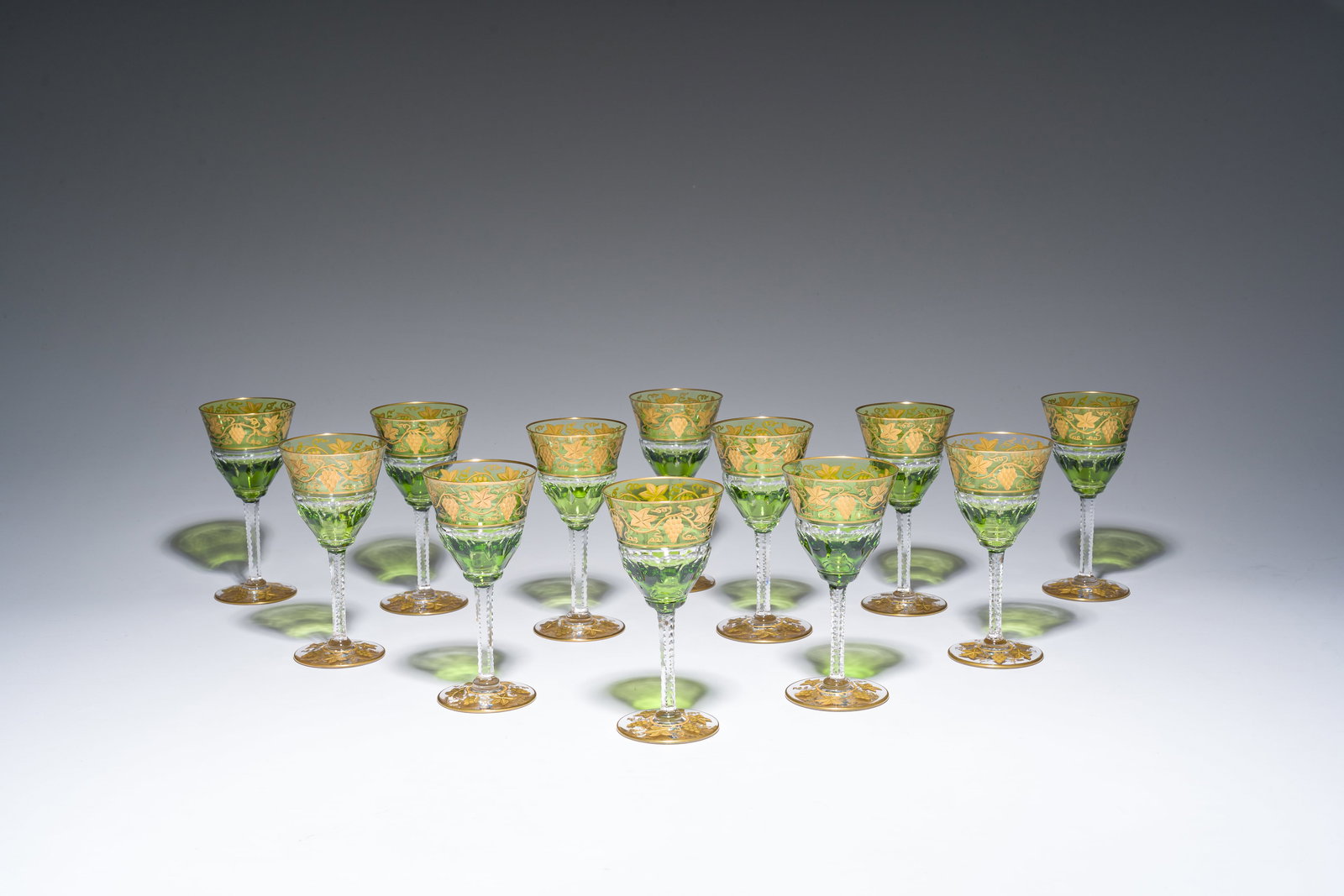 Twelve partly green-coloured overlay crystal cut white wine glasses with gilt grape design, model: Twelve partly green-coloured overlay crystal cut white wine glasses with gilt grape design, model 'Pampre d'or', Val Saint Lambert, 20th C. H 14,5 cm