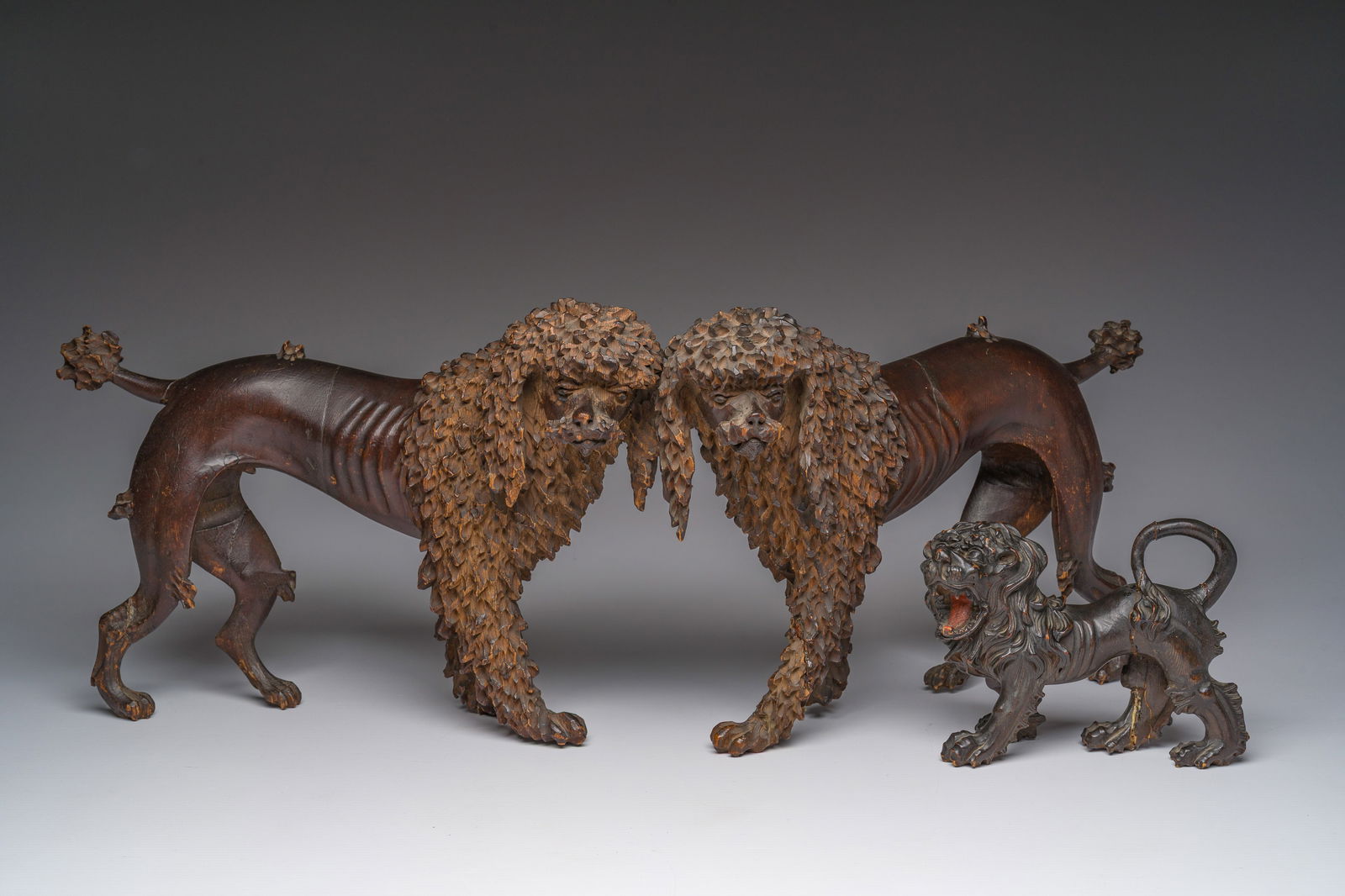 A pair of wood sculptures of poodles and one of a lion, possibly England, 18th/19th C.: A pair of wood sculptures of poodles and one of a lion, possibly England, 18th/19th C. H 22 - L 32 cm (the two dogs)H 12 - L 16 cm (the lion)