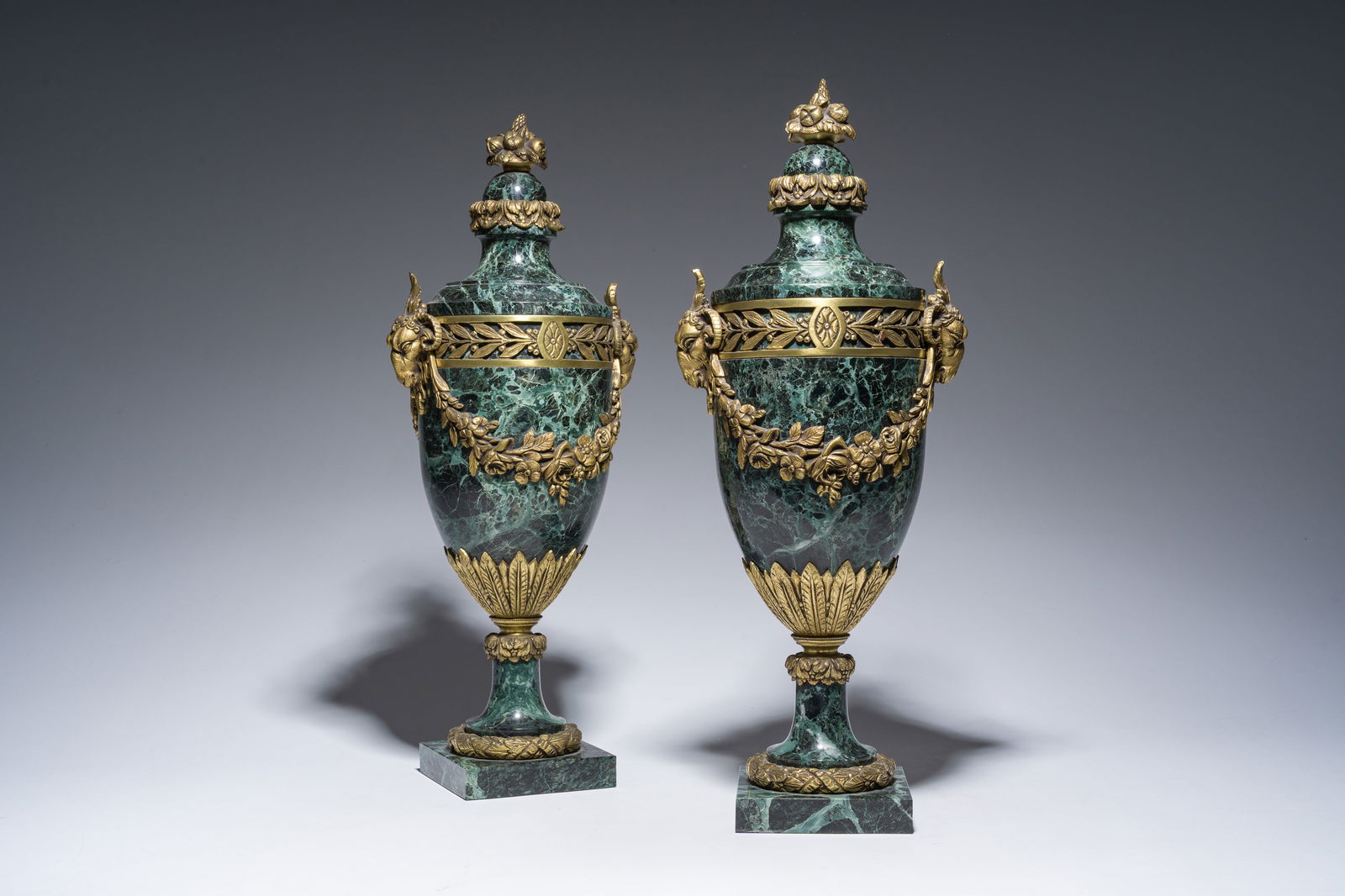 A pair of French Neoclassical vert de mer marble cassolettes mounted with gilt bronze rams' heads: A pair of French Neoclassical vert de mer marble cassolettes mounted with gilt bronze rams' heads and floral garlands, 19th/20th C. H 52 cm