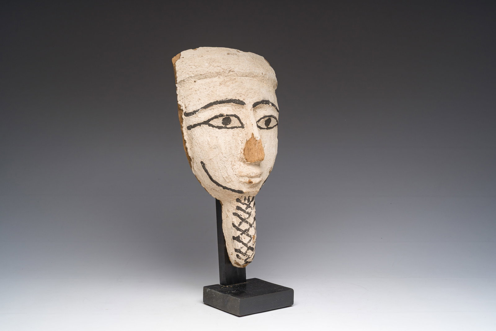 An Egyptian wooden sarcophagus mask with white stucco and black accents, Late Period, 6th-1st C. (1 of 6)