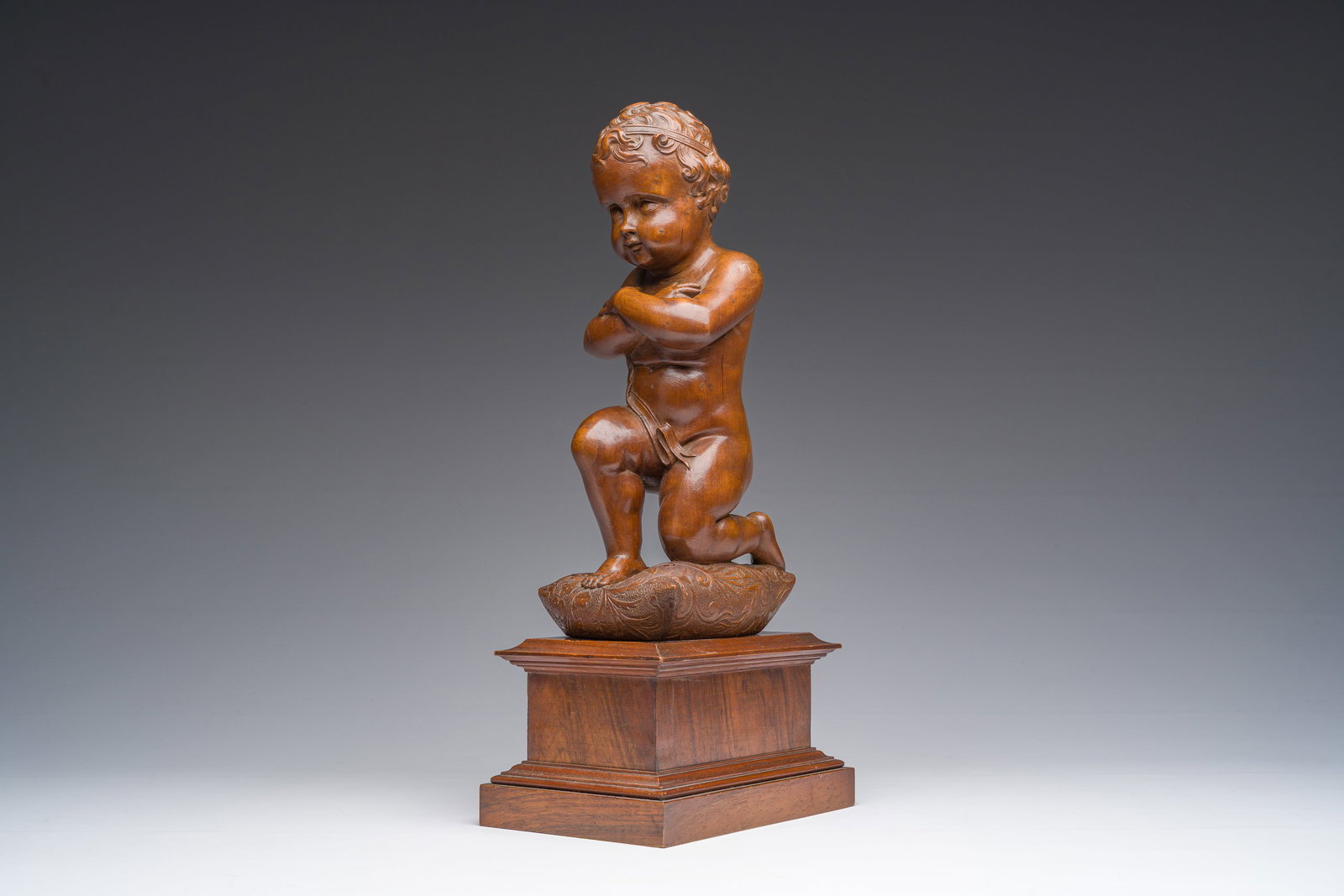 An Italian walnut sculpture of a youth kneeling on a cushion with floral design, 19th C. (1 of 7)
