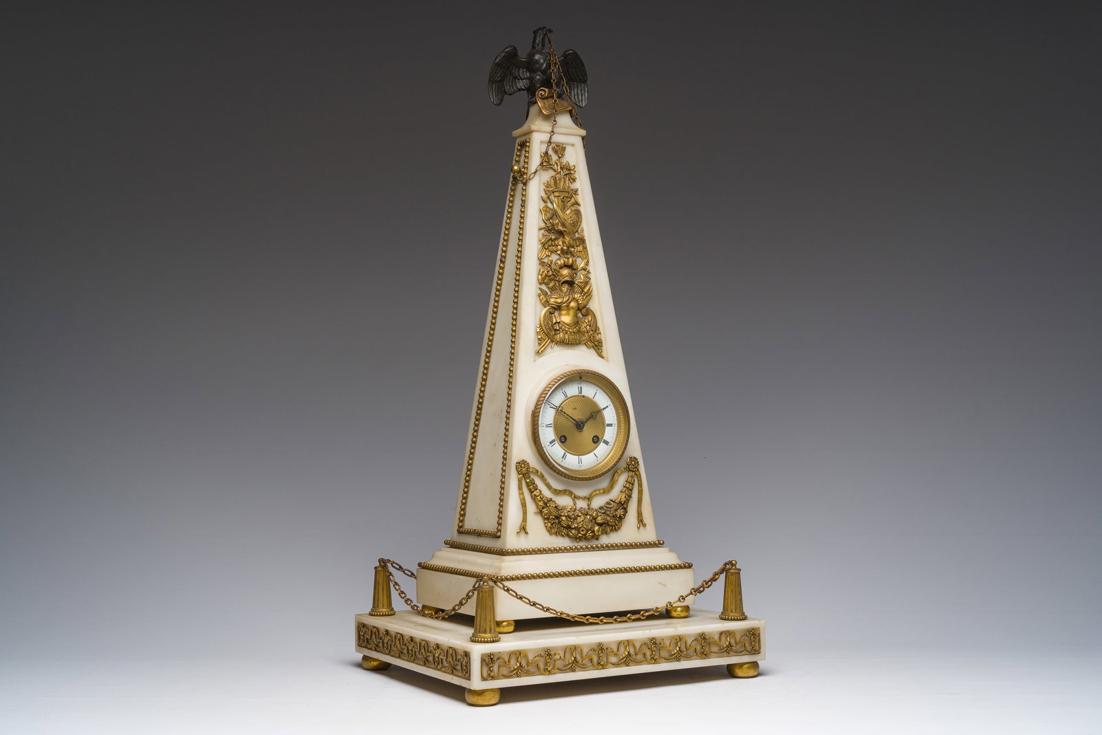 A rare French obelisk-shaped gilt bronze mounted white marble pendulum clock crowned with an eagle, (1 of 16)