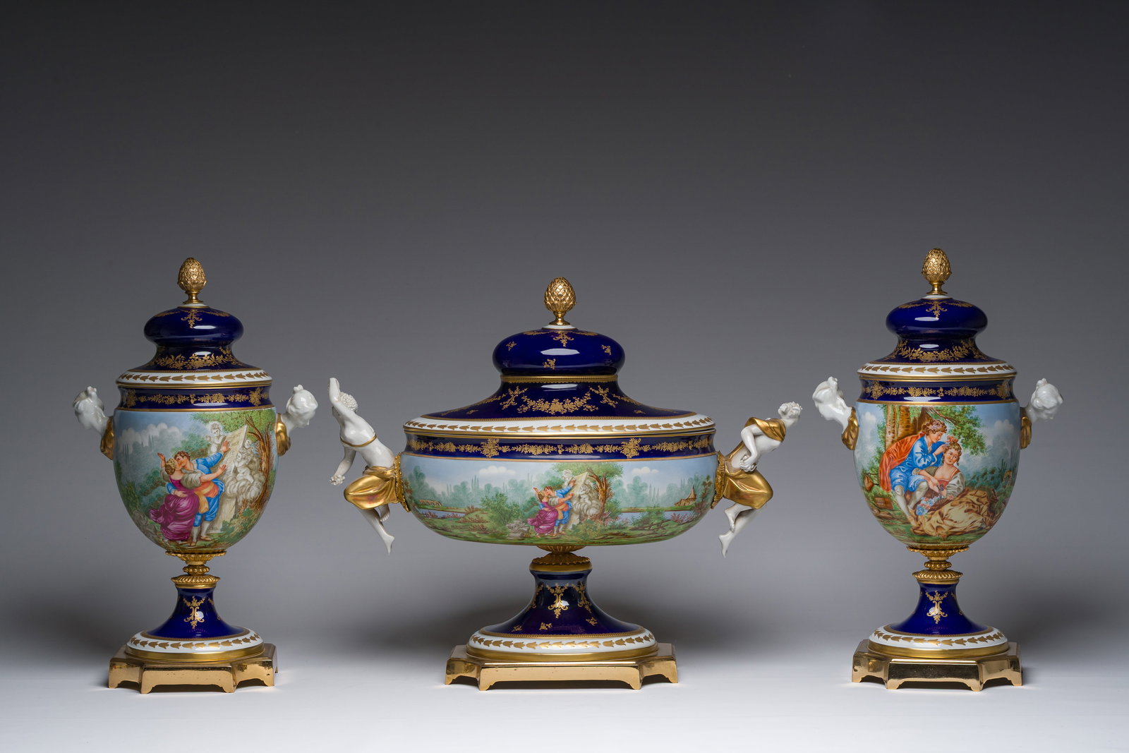 An Italian polychrome and partly gilt three-piece Sevres style garniture set with landscapes and (1 of 9)