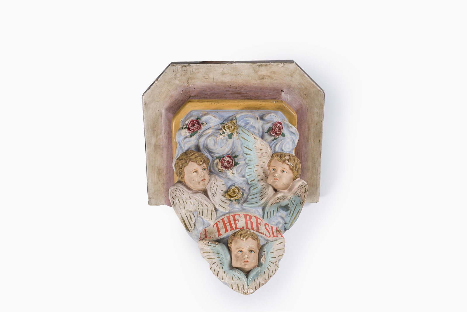 A polychrome decorated plaster 'Theresia' console with angels in the clouds surrounding a banner, (1 of 7)