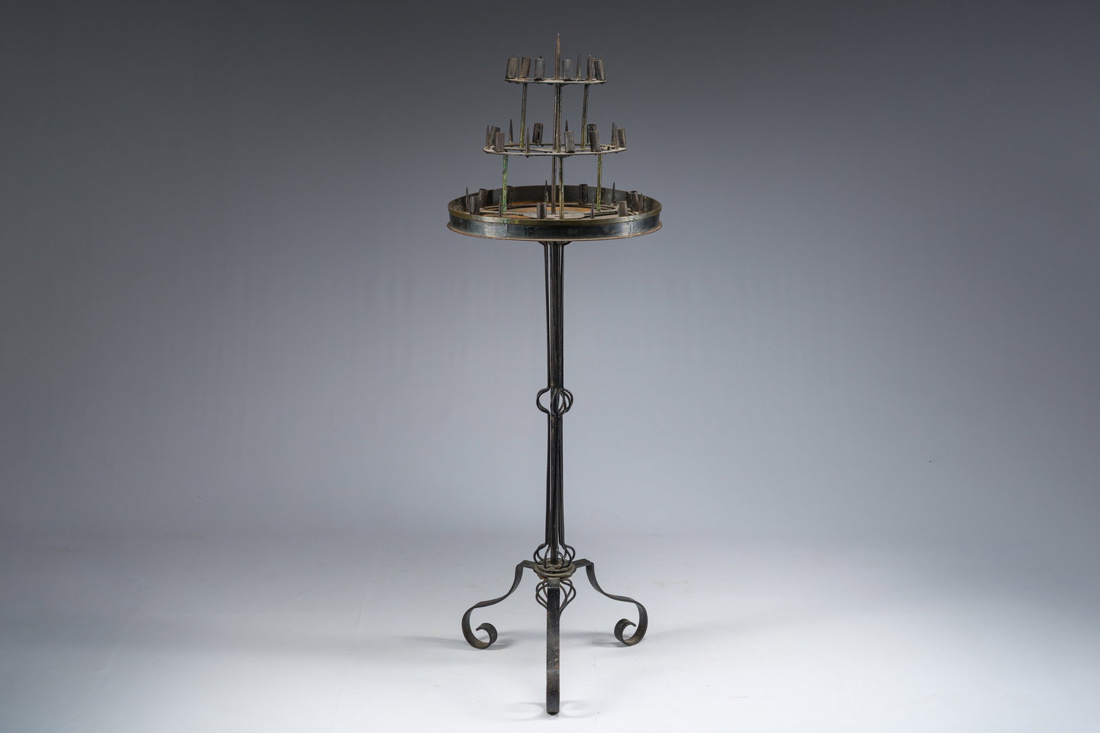 A Gothic revival patinated metal and copper tripod candlestick with three tiers, 19th/20th C. (1 of 8)