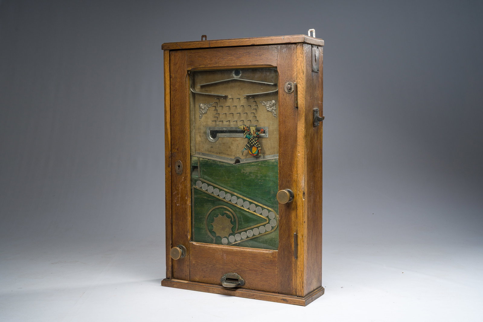 A German wooden 'Bajazzo' coin-operated gaming or slot machine with a harlequin, probably Jentzsch: A German wooden 'Bajazzo' coin-operated gaming or slot machine with a harlequin, probably Jentzsch and Meerz, early 20th C. H 73,5 - L 47,5 - D 16,5 cm