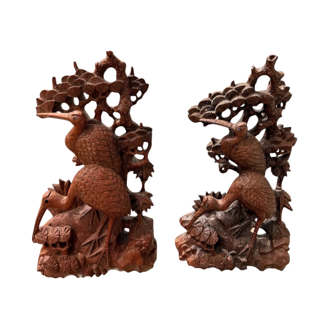 Pair of Chinese Carved Wood Crane Figures with Scholar’s Rock — One Damaged: A decorative pair of Chinese carved wood figures depicting cranes among stylized rock and foliage formations. The cranes, symbols of longevity and harmony in Chinese culture, are carved with detailed