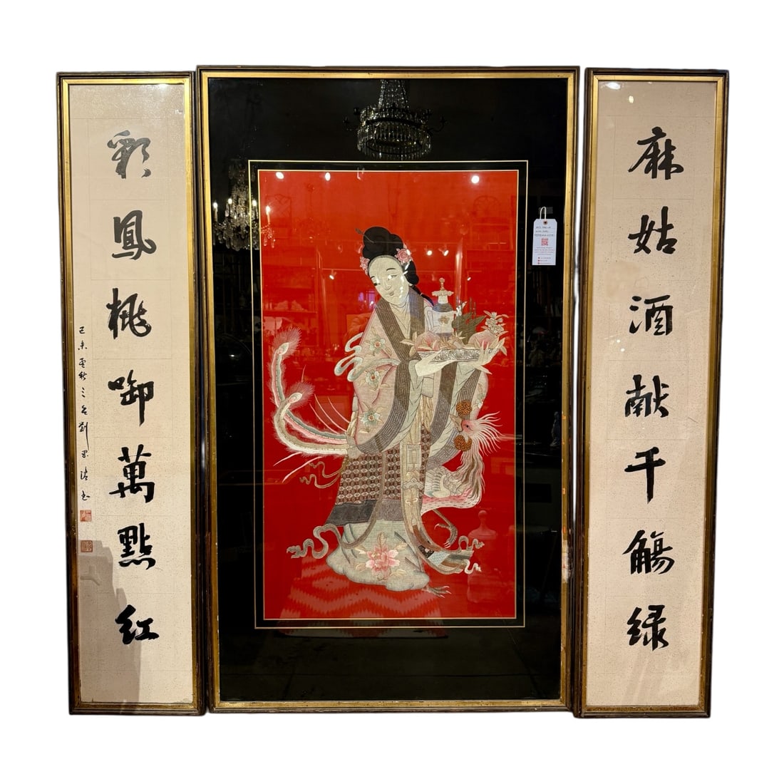 A monumental three-panel Chinese decorative wall ensemble formerly displayed at the well-known Hong: The set consists of a central silk screen or textile artwork depicting an elegant court lady or celestial goddess figure against a vibrant red ground, flanked by two vertical calligraphy panels