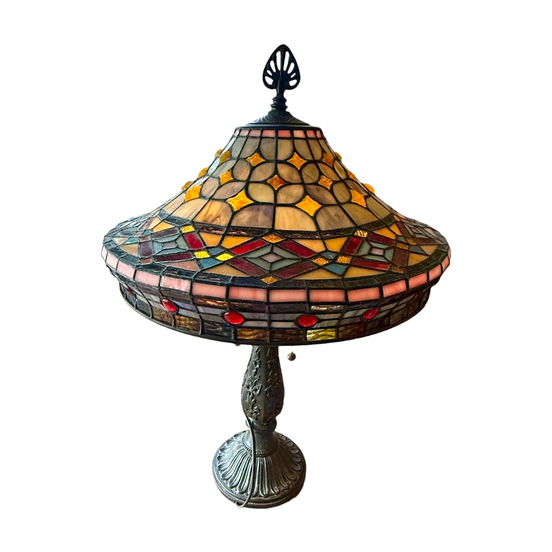 Tiffany-Style Stained Glass Table Lamp 28”: Decorative Tiffany-style table lamp featuring a large domed stained-glass shade composed of geometric panels in warm amber, cream, and burgundy tones with accent jewel details. The shade is mounted