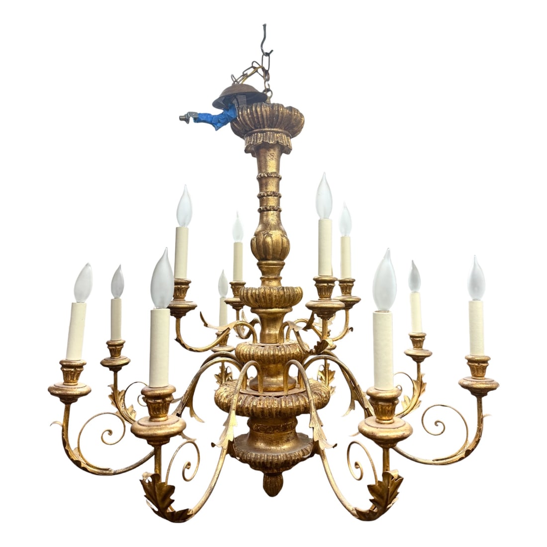 Large Giltwood and Metal Twelve-Light Chandelier: Large decorative chandelier featuring a richly carved and gilded central standard with tiered foliate and gadrooned details. Twelve scrolling metal arms are arranged across two levels, each supporting