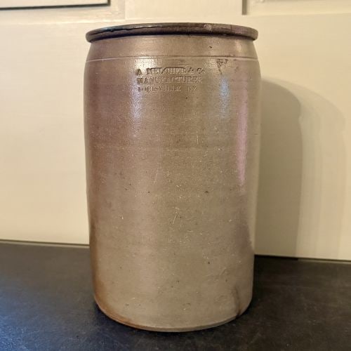 A. Melcher and Company Louisville Kentucky Salt Glazed Stoneware Jar 6"X10": This mid-19th century salt-glazed stoneware jar was manufactured by A. Melcher and Company in Louisville, Kentucky. The vessel features a cylindrical body that tapers slightly at the shoulder, leading