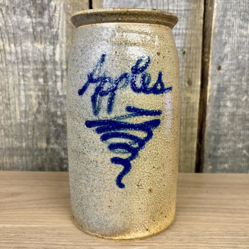 B. Stebner Hartville, Ohio Salt-Glazed Stoneware Apples Jar: A cylindrical salt-glazed stoneware storage jar attributed to potter Bernard Stebner of Hartville, Ohio. The vessel features a slightly flared rim and a flat base. The exterior surface displays a char