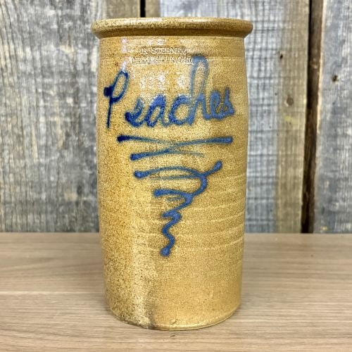 Bill Stebner Hartville Ohio Salt-Glazed Stoneware Peaches Jar: This cylindrical stoneware storage jar is a contemporary folk art piece produced by potter Bill Stebner. It is crafted from salt-glazed stoneware with a speckled tan finish. The front of the jar featu