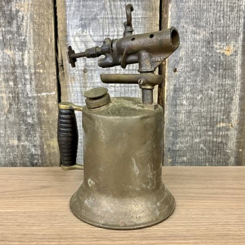 Antique Brass Gasoline Blowtorch with Cast Iron Burner and Ribbed Wood Handle: This is an antique gasoline blowtorch, a tool commonly used by plumbers and painters in the early 20th century. The piece features a cylindrical brass fuel tank with a distinctively flared base for st