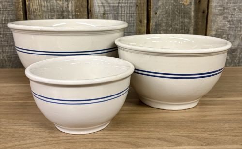 A Set of Three Gibson China Blue Banded Ceramic Nesting Mixing Bowls: A set of three graduated nesting mixing bowls produced by Gibson China. Each bowl is crafted from a heavy-duty glazed ceramic with an off-white or cream-colored body. The decorative scheme consists of