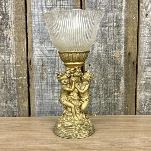 A Classical Style Putti Motif Table Lamp and a Ceramic Stoneware Jug: This lot includes two decorative objects. The first is a Classical Revival style table lamp featuring a cast metal base with an aged gilt finish. The base is sculpted with a group of two putti flankin