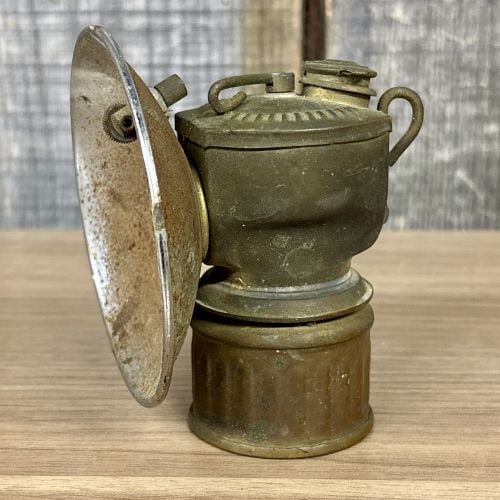 Antique Justrite Streamlined Brass Carbide Miner's Cap Lamp, c. 1923: This is an antique carbide, or acetylene, mining cap lamp manufactured by the Justrite Manufacturing Company. The device is constructed with a brass body and a plated metal reflector. The top surface 