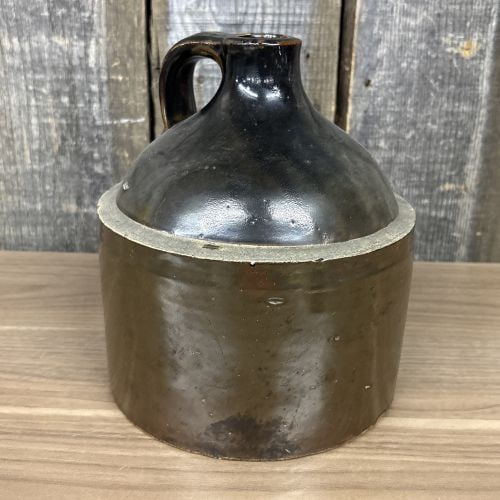 Antique Two-Toned Stoneware Beehive Jug: This antique stoneware vessel is a beehive or dome-top style whiskey jug. It features a cylindrical lower body transitioning into a sloping, dome-shaped shoulder, terminating in a narrow mouth with a 