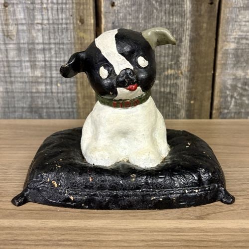 Antique Puppo Dog on Pillow Still Bank or Doorstop: This figure is identified as the Puppo model, attributed to A.C. Williams of Ravenna, Ohio, and is constructed of painted cast iron. The piece depicts a seated black and white dog, modeled after a Bos
