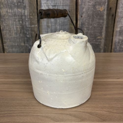 American Stoneware Harvest Jug with Molded Foliate Shoulder: This American stoneware harvest jug, also known as a mower's jug, features a cylindrical body and a rounded shoulder. The shoulder is ornamented with a molded foliate or stylized leaf design. The vess