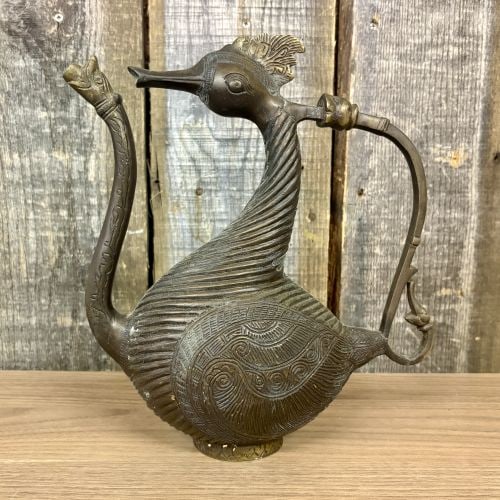 Indo-Islamic Style Cast Bronze Bird-Form Ewer with Makara Spout: A heavy cast metal vessel, likely brass or bronze, in the form of a mythical bird, typically identified as a hamsa or swan. This ewer is crafted in a South Asian folk or tribal style, exhibiting the c