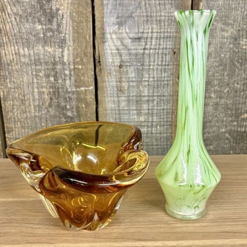 Two Pieces of Vintage Art Glass Including a Freeform Amber Bowl and a Green Slag Glass Bud Vase: This lot features two distinct pieces of vintage decorative glass. The first is a hand-blown amber art glass bowl or ashtray designed in an organic freeform style. The piece features four pulled lobes