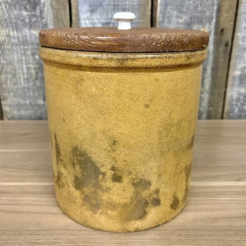 American Yellow Glazed Stoneware Storage Jar with Wooden Lid: A cylindrical stoneware storage jar or crock featuring a straight-sided body with a slightly flared, rounded rim and a flat base. The piece is finished with a mottled yellow-to-buff glaze on the exter