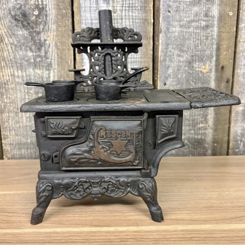 Crescent Foundry Co. Miniature Toy Kitchen Range with Accessories: This miniature kitchen range is a cast iron toy manufactured by the Crescent Foundry Co. of St. Louis, Missouri. The front oven door bears the maker name Crescent in raised relief, with the initial le