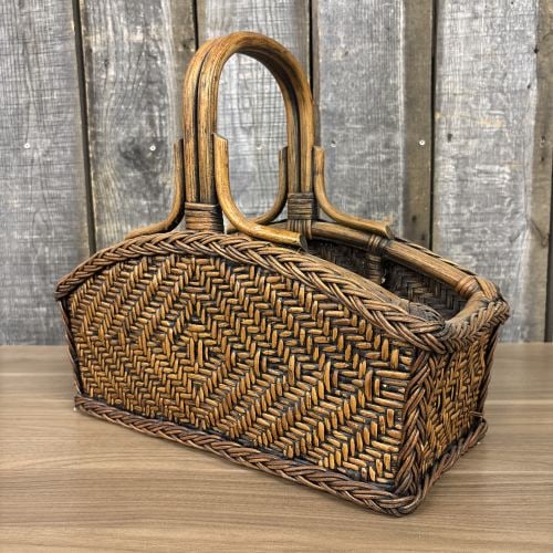 Vintage 1970s Woven Rattan and Wicker Magazine Rack Basket Carrier: This vintage hand-woven basket carrier is constructed from rattan, wicker, and wood, and is suitable for use as a magazine rack or storage caddy. The item features a prominent arched double-pole ratta