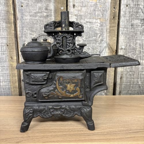 Crescent Miniature Toy Kitchen Stove with Cookware Accessories: This miniature toy kitchen stove features the embossed name Crescent on the front oven door and is marked Taiwan on the reverse. The item is constructed from cast iron with a black painted finish and 