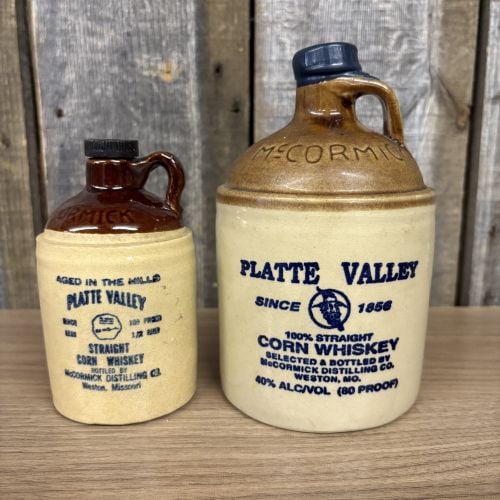 Two McCormick Platte Valley Straight Corn Whiskey Stoneware Jugs: This lot consists of two two-tone stoneware whiskey jugs produced for Platte Valley Straight Corn Whiskey by the McCormick Distilling Company of Weston, Missouri. The first jug is a 750ml vessel featu