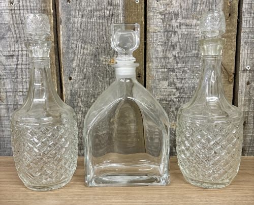 A Trio of Glass Spirit Decanters Including a Pair of Cut Glass and One Luigi Bormioli Style Example: This lot features a trio of glass decanters. Included is a matching pair of spirit decanters with a bulbous form and faceted, fluted necks. The lower sections of the bodies are decorated with a deep d