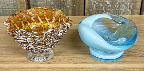 Two Pieces of Contemporary Hand-Blown Art Glass: This lot includes two contemporary hand-blown art glass bowls. The first piece is a footed glass bowl characterized by a flared, ruffled rim. The exterior features a fine mottled or spotted pattern in