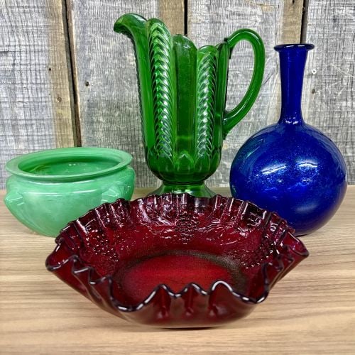 An Assortment of Vintage Decorative Glassware: This assortment of vintage decorative glass features four distinct pieces including examples of pressed and hand-blown manufacturing. Included is a tall emerald green pitcher in a ribbed herringbone p