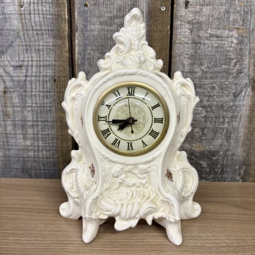 Vintage Lanshire Electric Ceramic Mantel Clock in Rococo Style: This vintage electric mantel clock features an ornate cream-colored glazed ceramic case in the Rococo Revival style. The case is detailed with prominent scrolling, shell-like motifs, and a raised reli