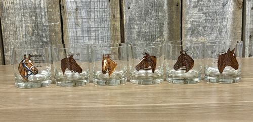 A Set of Six Vintage Thoroughbred Triple Crown Winners Lowball Glasses: A set of six glass lowball or rocks drinking vessels featuring prominent American Thoroughbred Triple Crown champions. Each glass is constructed of clear glass with a weighted base. One side displays 