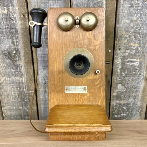 Chicago Telephone Supply Company Antique Oak Wall-Mounted Magneto Crank Telephone: An antique wall-mounted magneto telephone featuring a solid oak cabinet with a natural finish. This early 20th-century unit was produced by the Chicago Telephone Supply Company of Elkhart, Indiana. Th