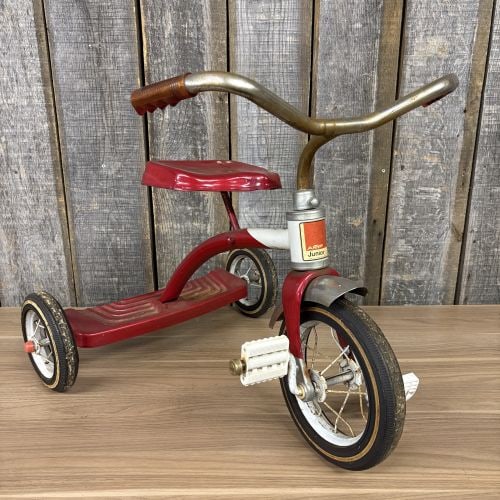 Vintage AMF Junior Tricycle: This is an AMF Junior model children's tricycle constructed with a pressed steel frame and a two-step rear platform. The tricycle features a contoured metal seat and a front wheel with a direct-drive 