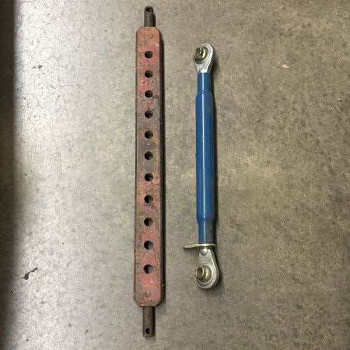 A Pair of Tractor Hitch Components Including Multi-Hole Drawbar and Adjustable Top Link: This lot comprises two metal agricultural hitch components. The first item is a multi-hole drawbar constructed of heavy-duty steel with a red painted finish. It features a rectangular central section 
