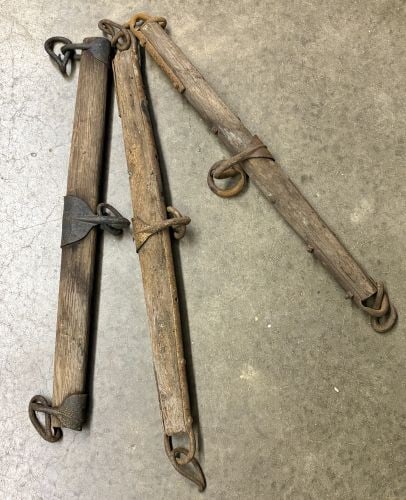 A Trio of Antique Wooden and Iron Horse-Drawn Singletrees: This lot consists of three antique wooden singletrees, also known as whippletrees, which were used to balance the pull of a draft animal in horse-drawn harness systems. Each singletree is constructed 