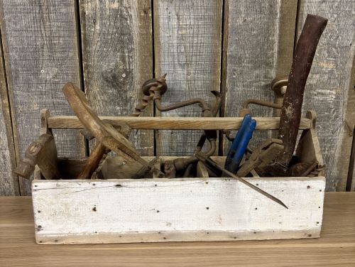 An Assortment of Antique and Vintage Hand Tools in a Primitive Wooden Tool Tote: This lot comprises an assortment of antique and vintage manual hand tools presented in a primitive, handmade wooden carpenter's tool tote. The tote is constructed from solid wood planks and features a