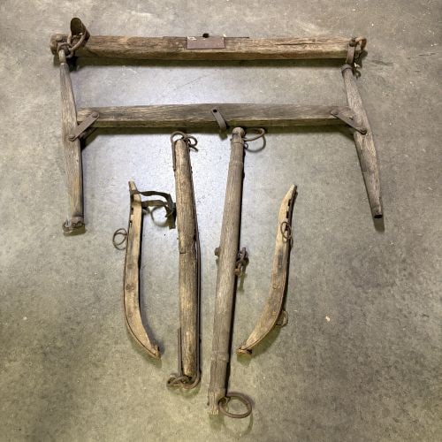 An Assortment of Antique Wood and Iron Horse-Drawn Vehicle and Harness Components: This lot consists of a collection of antique horse-drawn vehicle and harness components constructed from heavy timber and hand-forged or early industrial iron hardware. The assembly includes a large w