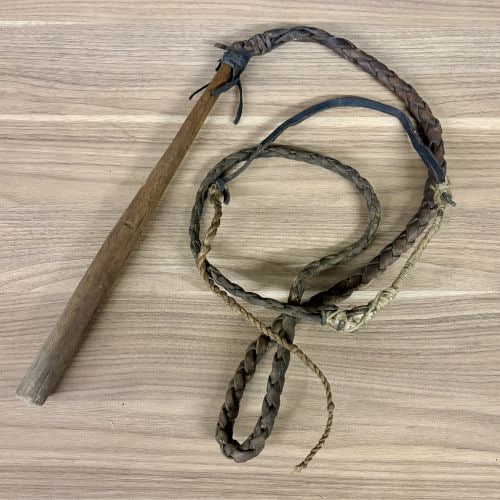 Antique Braided Leather Quirt with Turned Wood Handle: This antique or vintage equestrian quirt features a turned hardwood handle and a multi-strand braided lash. The handle is constructed from a single piece of wood, showing a tapered form and a naturall