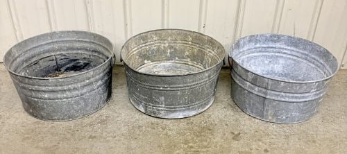 Three Vintage No. 2 Galvanized Steel Round Wash Tubs: A group of three vintage utilitarian round wash tubs constructed from galvanized steel. Each tub features formed sheet metal walls with vertical seams and multiple horizontal corrugated ribs for struc